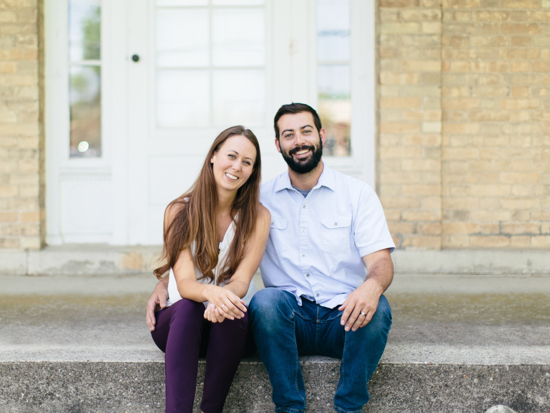 Whitney and Eric Shneyder sitting on the front porch of their property, Rustic Manor 1848