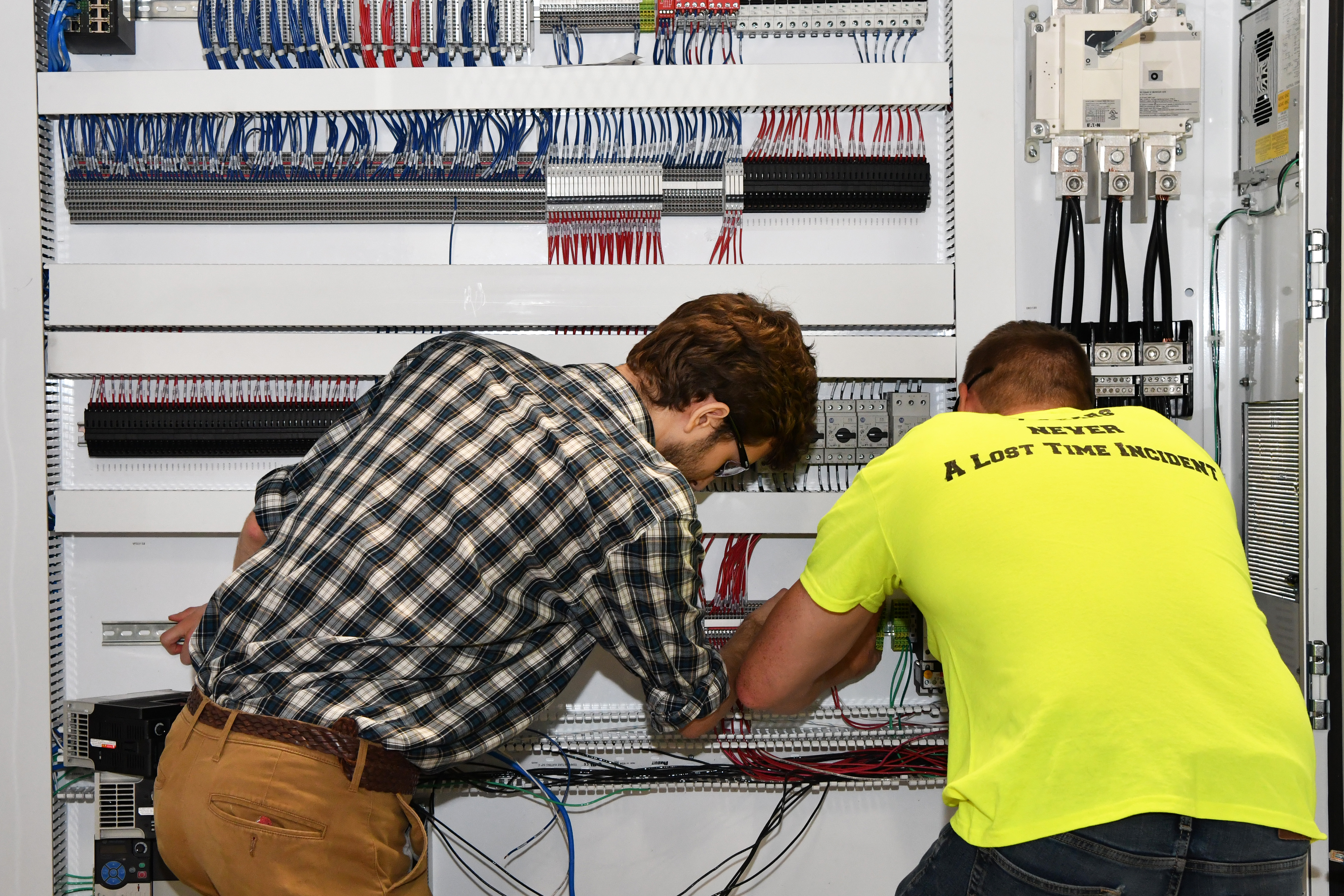 Employees at Automation Solutions work on control panel.
