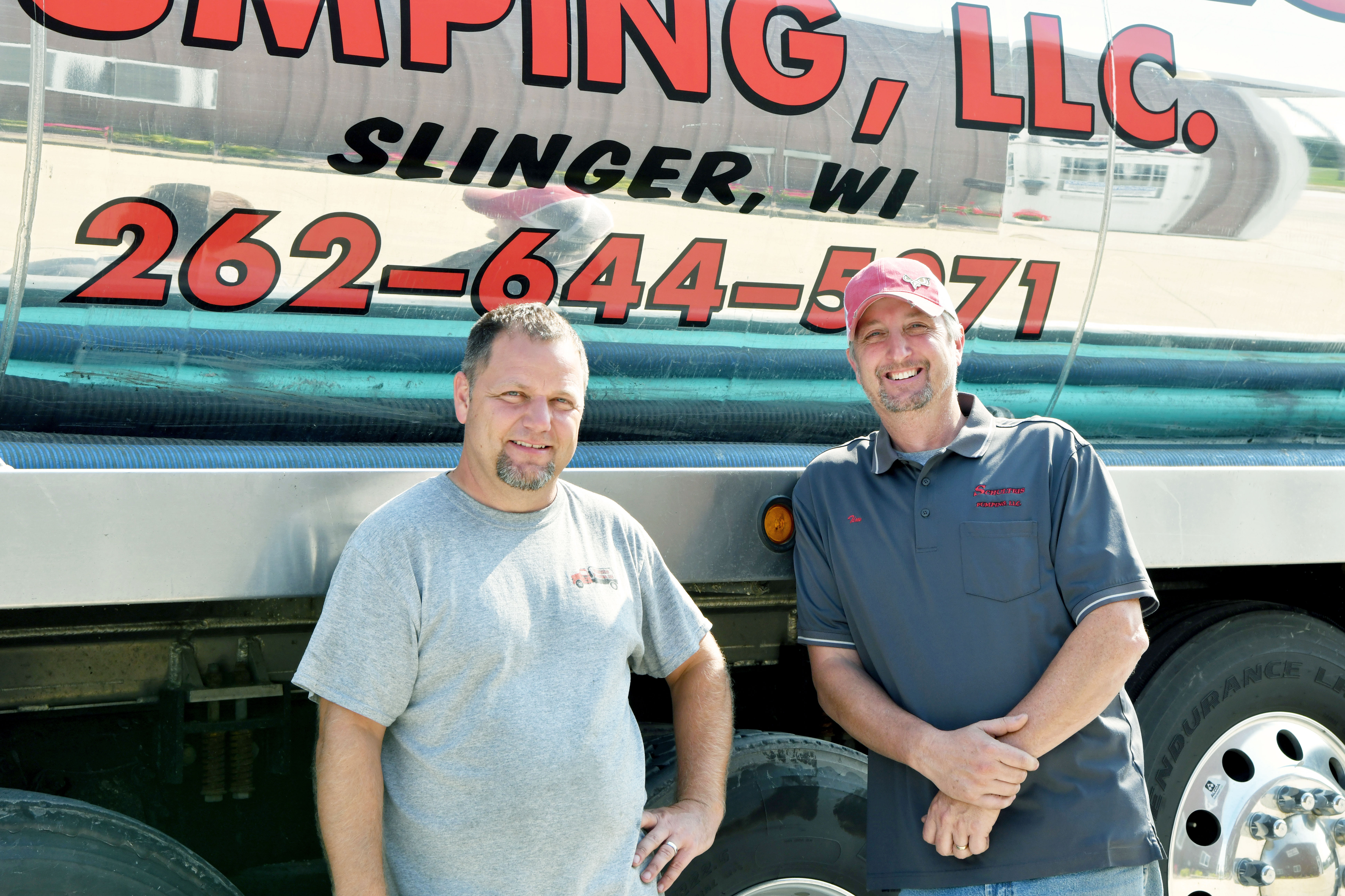 Tim Schulteis and Nathan Hill lean against a Schulteis Pumping truck.